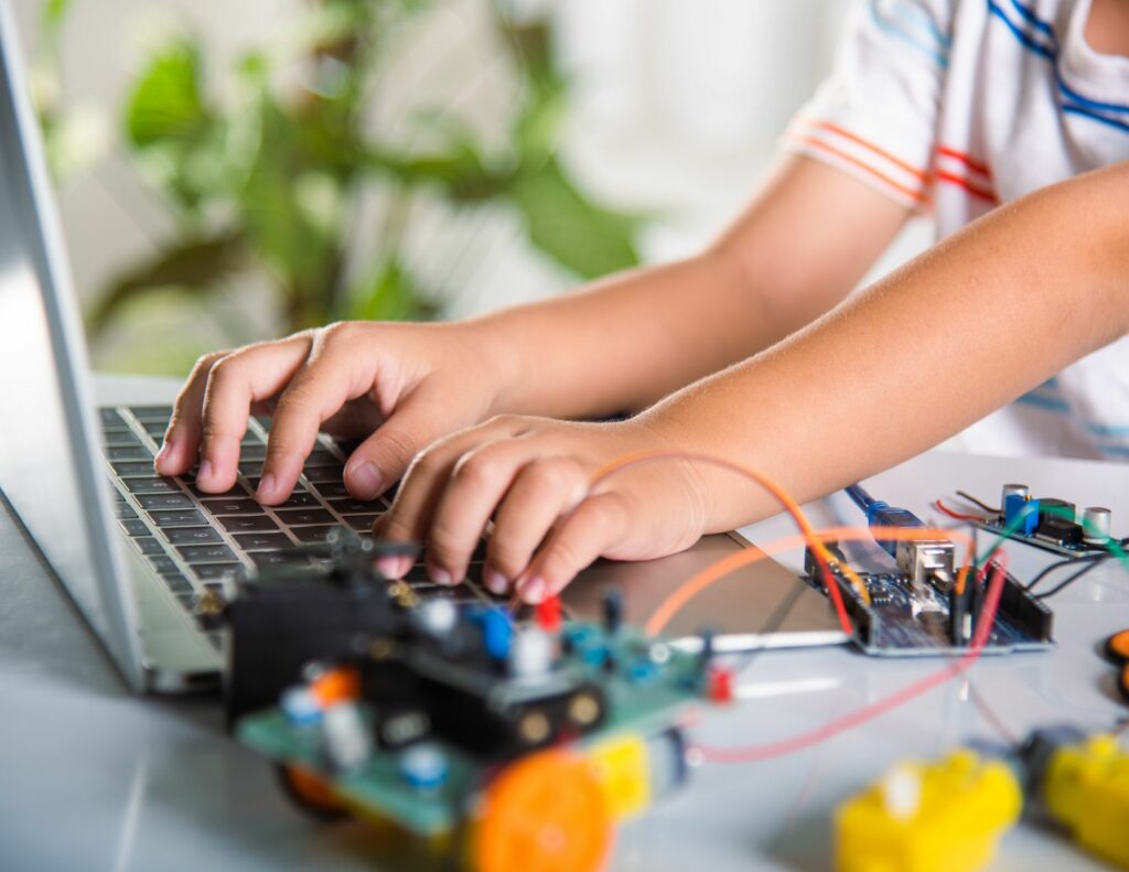 Child working on a laptop with circuits on the tabletop